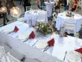 Elegancko nakryte stoły weselne z czerwonymi serwetkami i kwiatami. Zastanawiasz się, ile kosztuje uczesanie na wesele?