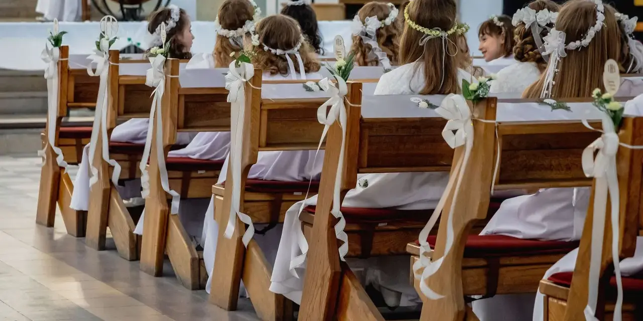 Dzieci w bieli, z wiankami na głowach, siedzą w ławkach kościelnych. Zastanawiasz się, ile trwaja komunie? To ważny dzień dla nich.