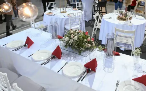Elegancko nakryte stoły weselne z czerwonymi serwetkami i kwiatami. Zastanawiasz się, ile kosztuje uczesanie na wesele?