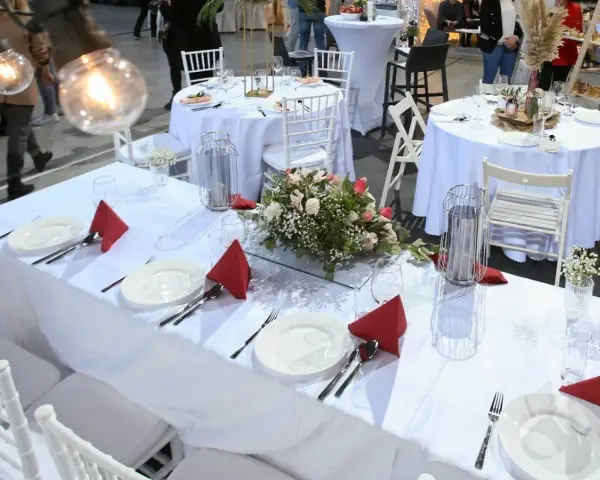 Elegancko nakryte stoły weselne z czerwonymi serwetkami i kwiatami. Zastanawiasz się, ile kosztuje uczesanie na wesele?
